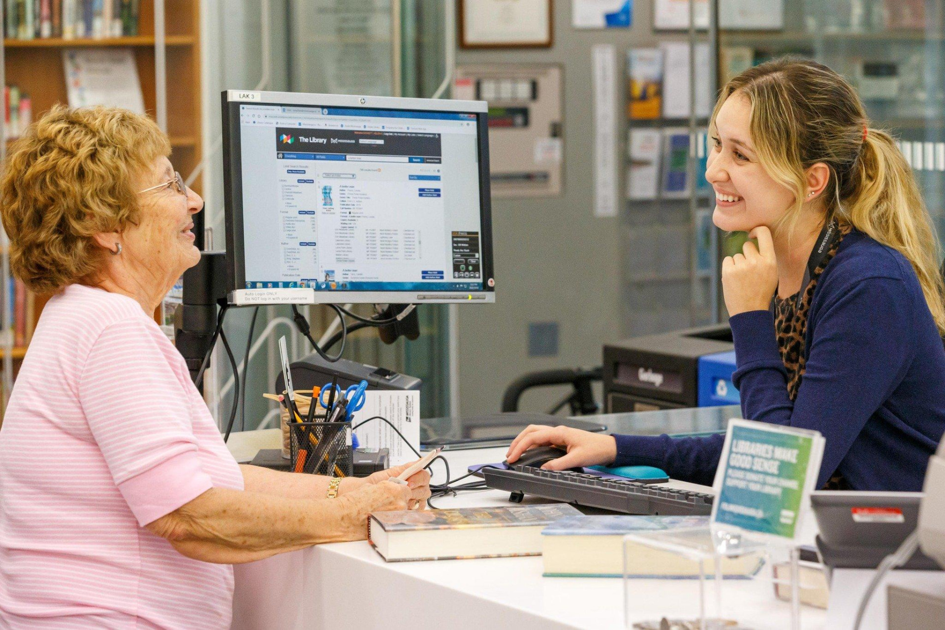 A library staff member helping a senior resident